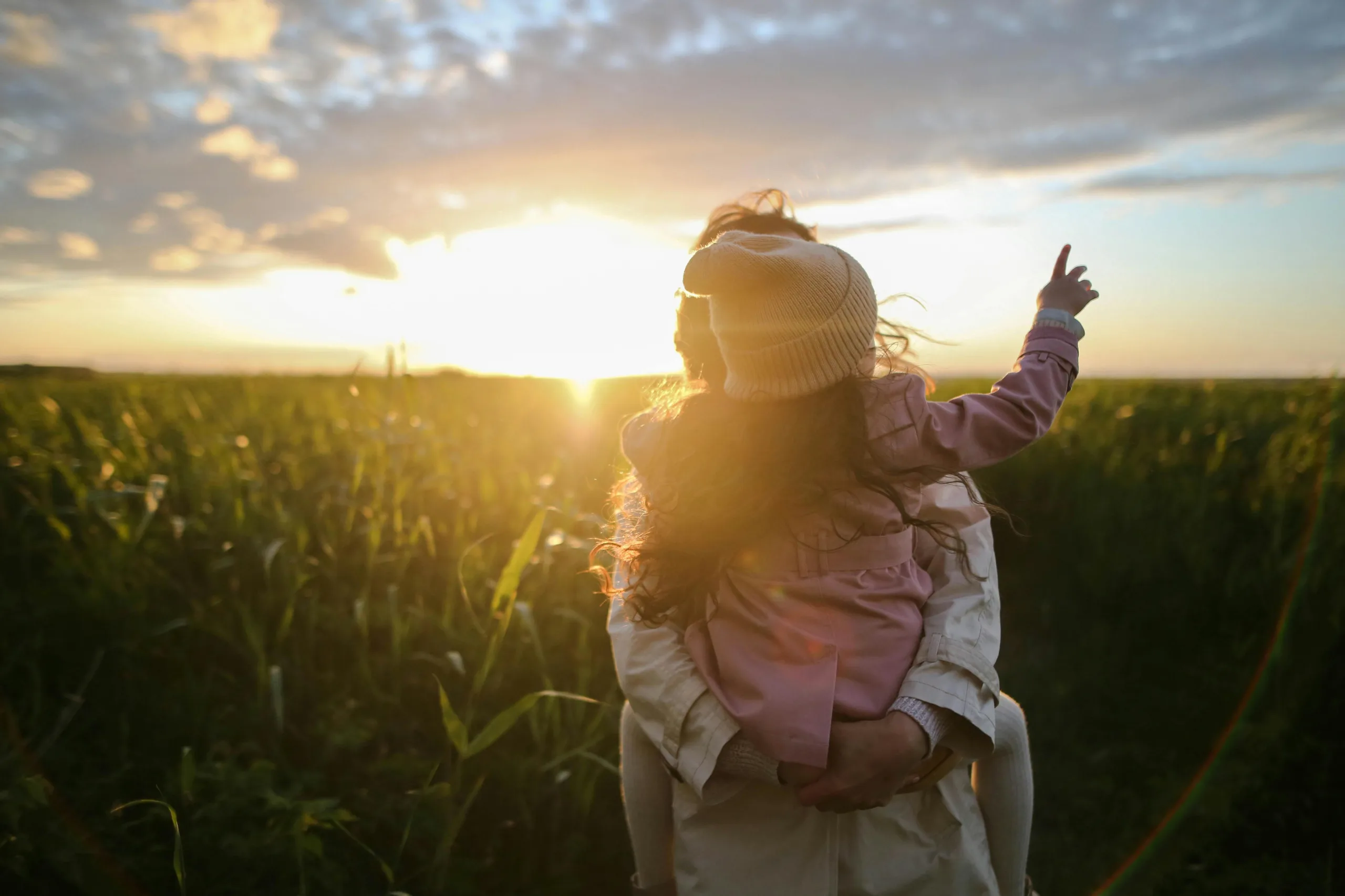 decorative image to accompany blog on wills. sunset scene with woman holding a toddler aged child. the child has her back to the camera and is obscuring the woman's face.