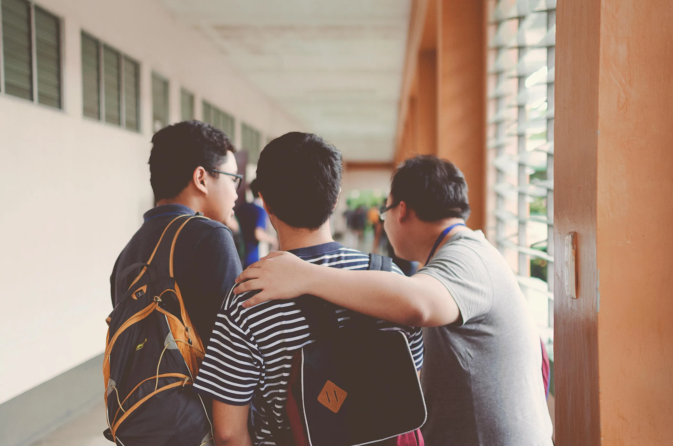 decorative image to accompany student loans blog post. image of three student friends who are facing away from the camera. they all wear backpacks.