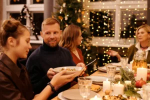 decorative image of family gathered at dinner table passing food around and smiling. Christmas financial planning.