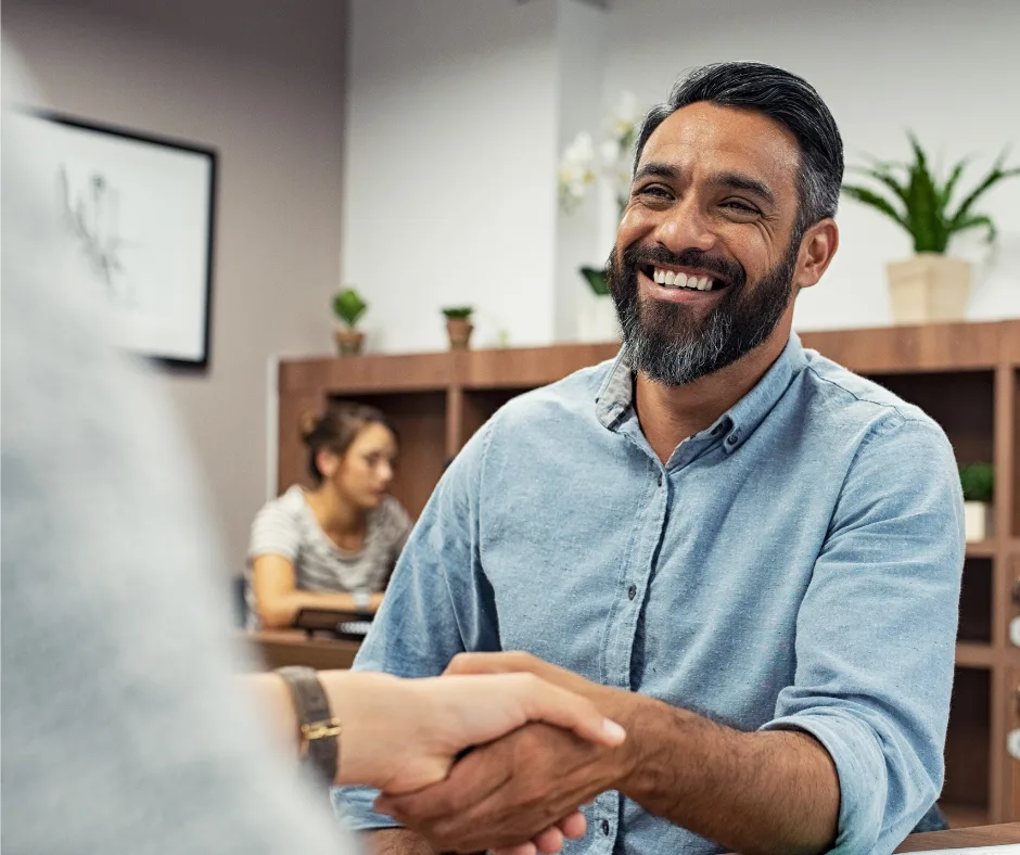asian man with beard shakes hands with someone out of shot. he is smiling. to accompany blog on business owners