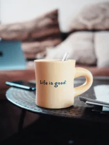 decorative image to accompany blog post on living a great life and financial security. photo of a mug with the words life is good on it sitting on a plate.