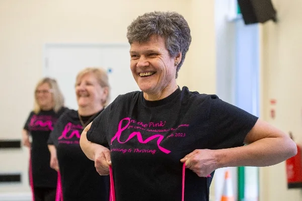 Cancer Active Recovery Support (C.A.R.S.) In the Pink programme. The Chesterton House Foundation awarded a grant. This is an image to support the blog post, which shows 3 women in black t-shirts taking part in a movement group. They are all smiling.